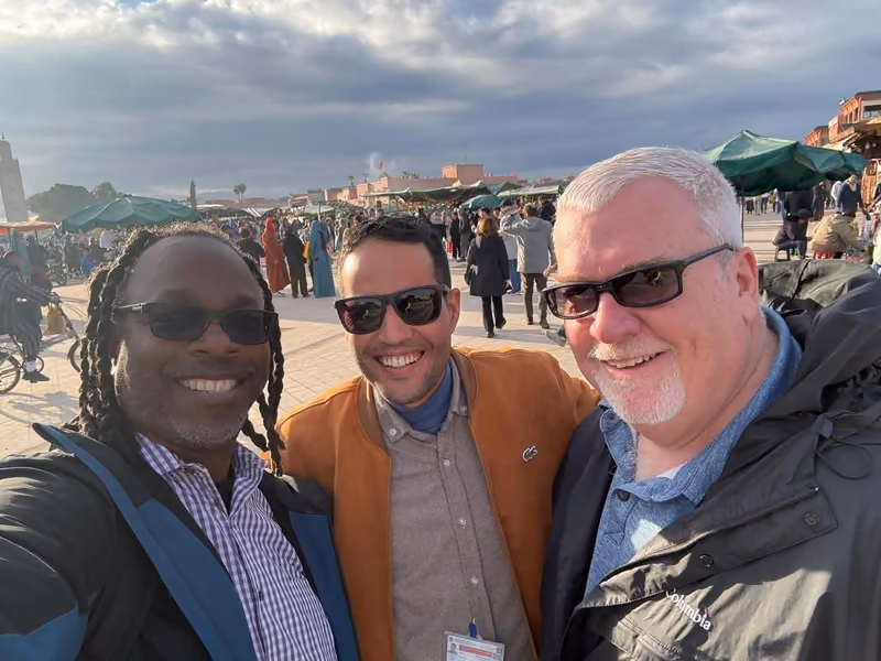 Three guests smiling on Jemaa el-Fna square at dusk