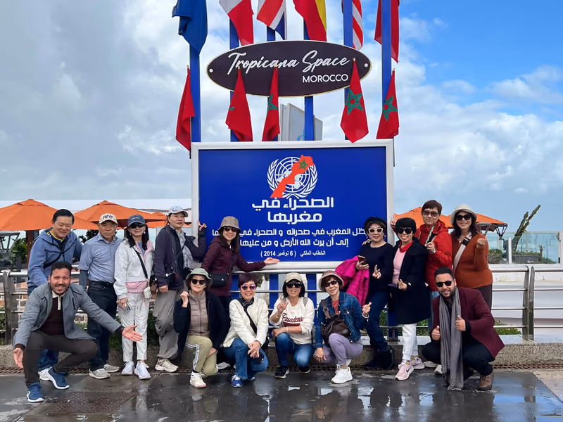 A full tour group gathered at a Moroccan coastal landmark