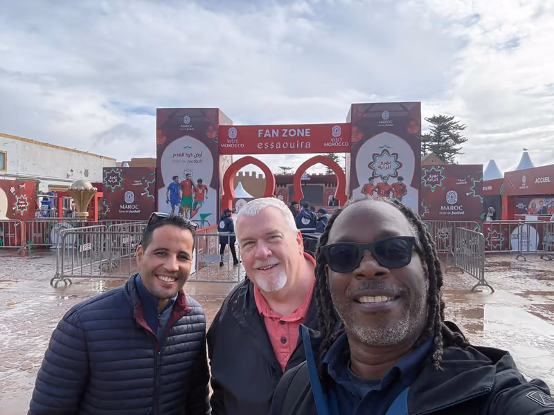 Three travelers at the Essaouira fan zone on a grey-sky day