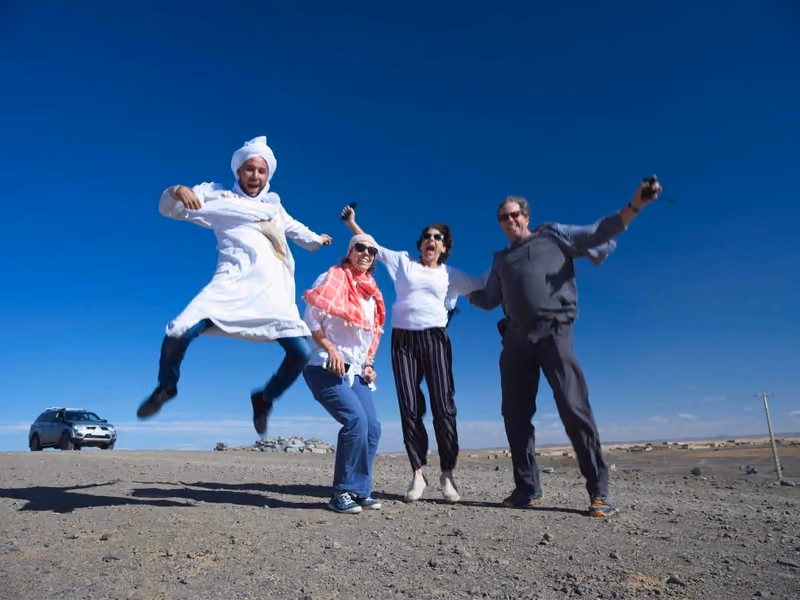 Guests leaping for joy with their guide on a clear desert day