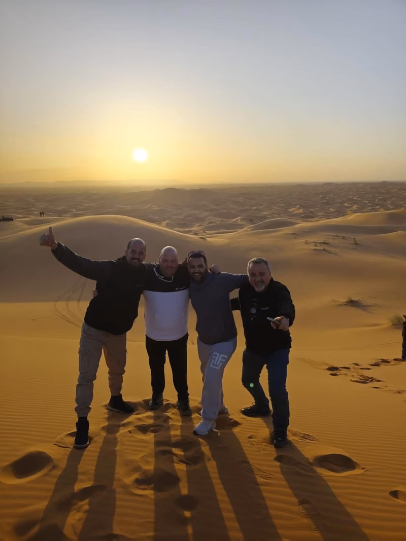 Four friends arm in arm as the sun sets over the Erg Chebbi dunes